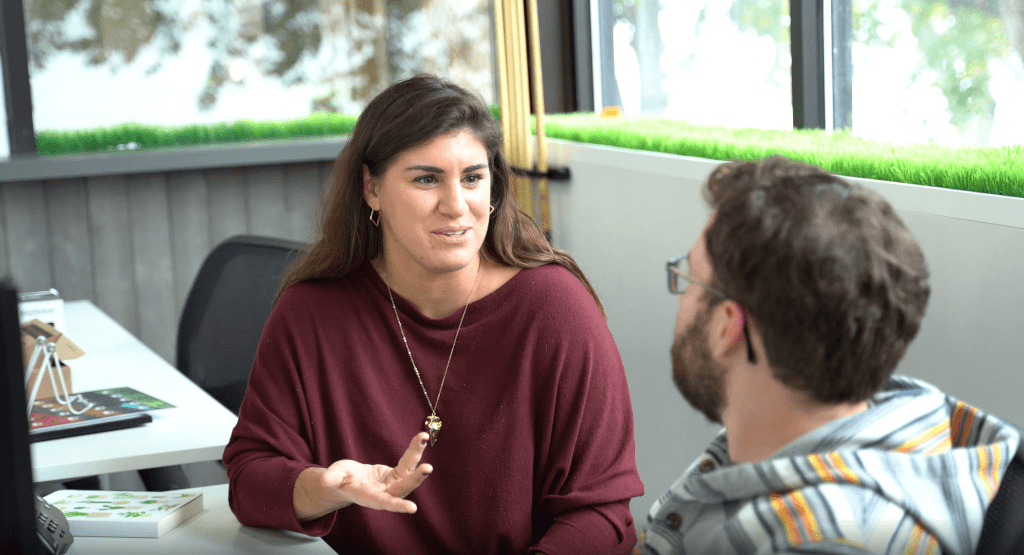 una mujer con un jersey rojo habla con un hombre